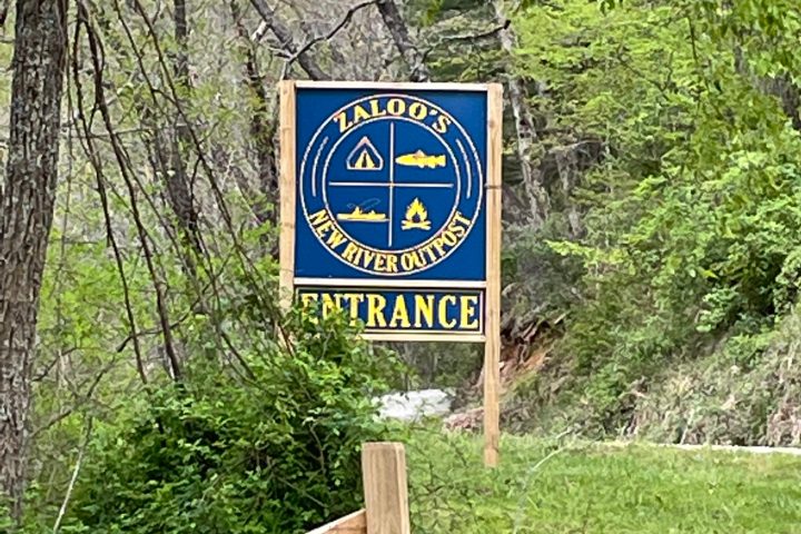 a sign on a fence next to a forest